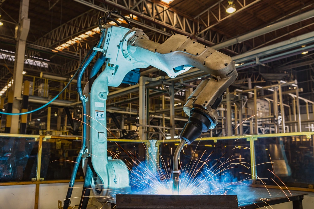 Industrial robotic arm performing welding with sparks flying in factory setting