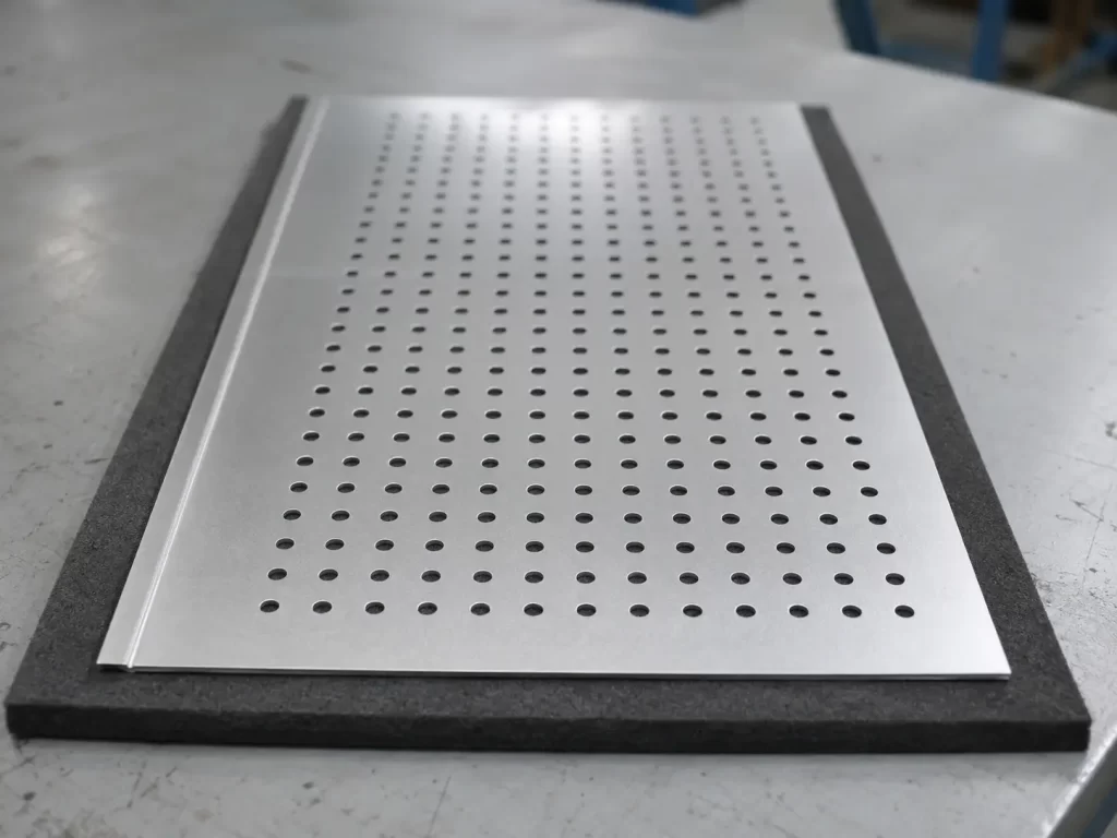 Close-up of CNC punched aluminum sheet showing hole diameter, pitch, and edge distance.