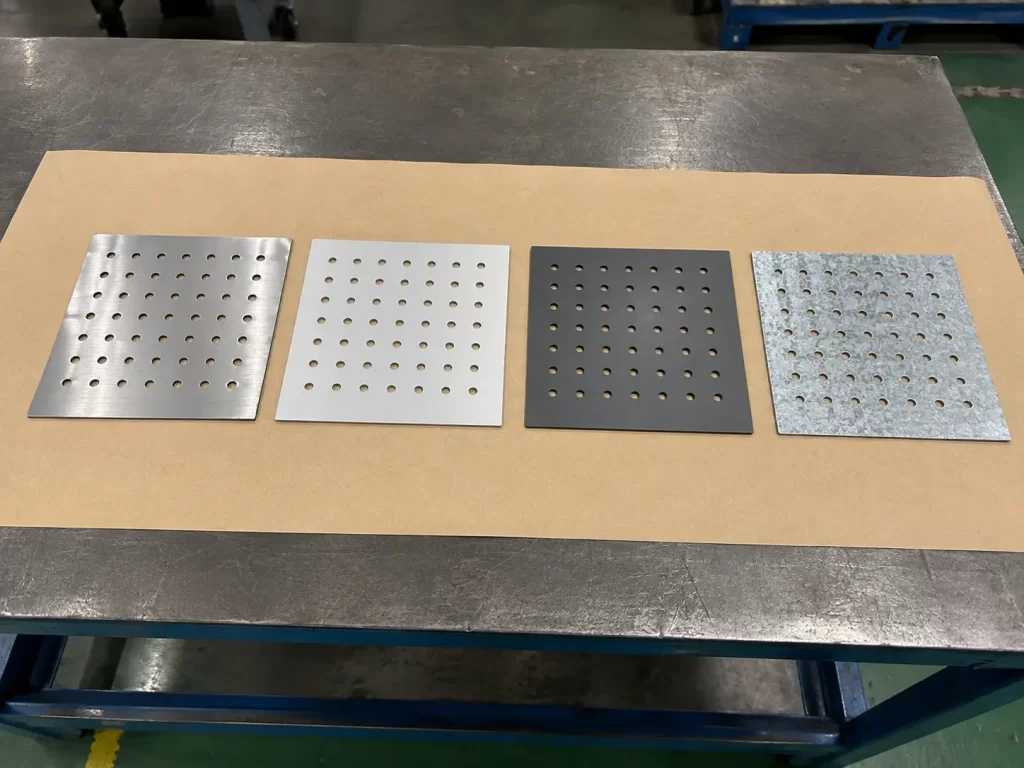 Punched sheet metal samples in stainless steel, aluminum, carbon steel, and galvanized steel.